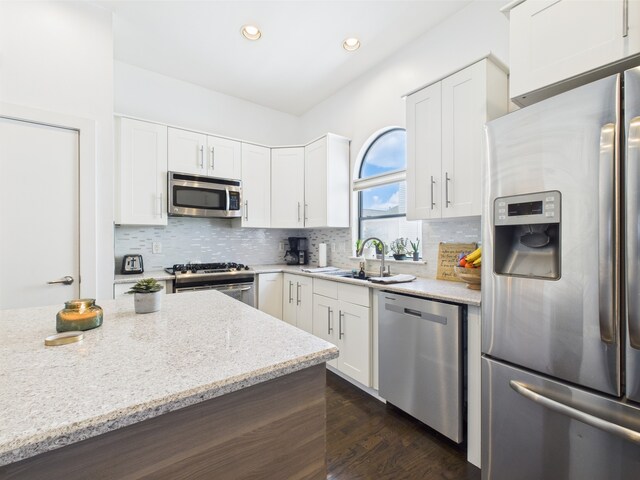 5810 Darling St Unit F, Houston, TX 77007 - kitchen with stainless steel appliances, light stone countertops, white cabinets, decorative backsplash, and recessed lighting