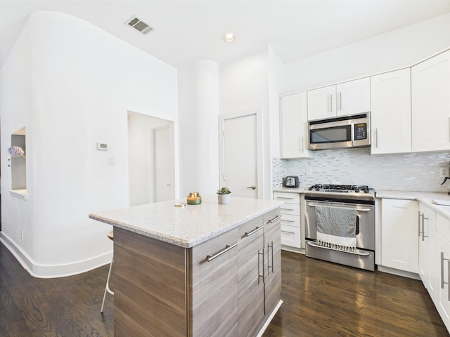 5810 Darling St Unit F, Houston, TX 77007 - kitchen with stainless steel appliances, dark wood-style floors, backsplash, white cabinetry, and light stone counters