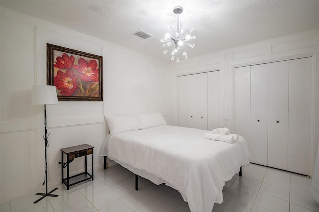 10730 Braes Bayou Dr, Houston, TX 77071 - bedroom featuring a decorative wall, a chandelier, multiple closets, and light tile patterned floors