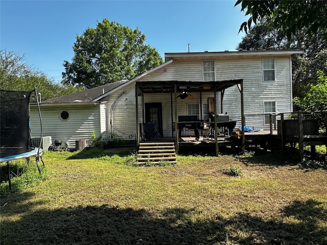 31730 Waller Tomball Rd, Waller, TX 77484 - rear view of property featuring a trampoline, a yard, a wooden deck, and a ceiling fan