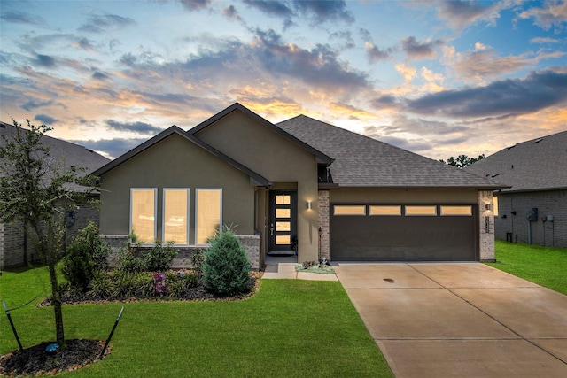 14320 Yellow Hawthorn Ct, Conroe, TX 77384 - view of front of house featuring a garage, driveway, a yard, stucco siding, and a shingled roof