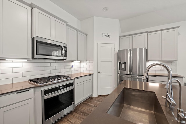 14320 Yellow Hawthorn Ct, Conroe, TX 77384 - kitchen with stainless steel appliances, dark countertops, dark wood-style floors, decorative backsplash, and white cabinets
