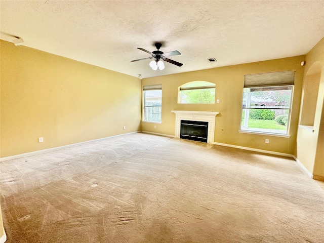 2716 W Oaks Cir E, Pearland, TX 77584 - unfurnished living room with healthy amount of natural light, a ceiling fan, a textured ceiling, light colored carpet, and a fireplace with flush hearth