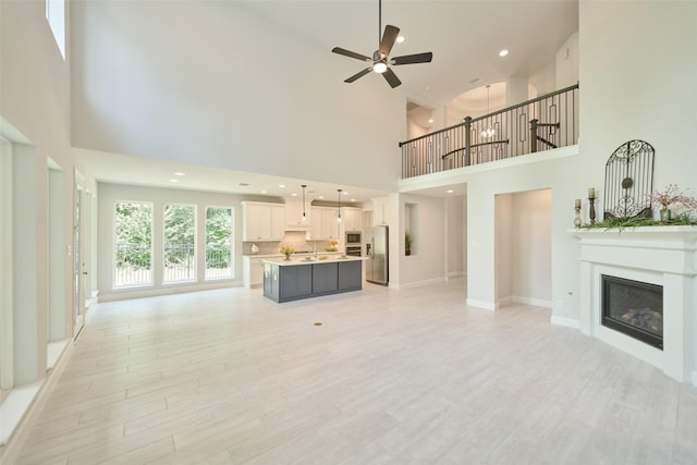 237 Patina Sorrel Dr, Montgomery, TX 77316 - unfurnished living room featuring a towering ceiling, ceiling fan, a glass covered fireplace, light wood-style floors, and recessed lighting