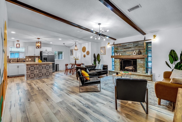 5918 Lattimer Dr, Houston, TX 77035 - living room featuring a chandelier, light wood-type flooring, beam ceiling, recessed lighting, and a stone fireplace