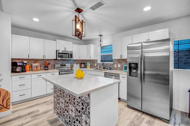 5918 Lattimer Dr, Houston, TX 77035 - kitchen featuring appliances with stainless steel finishes, white cabinetry, light wood finished floors, tasteful backsplash, and decorative light fixtures