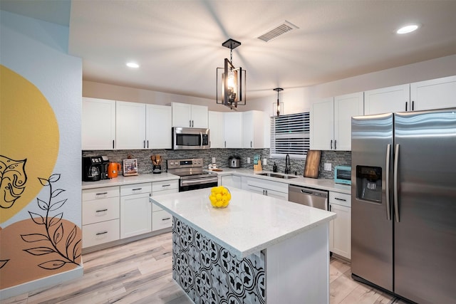 5918 Lattimer Dr, Houston, TX 77035 - kitchen with appliances with stainless steel finishes, decorative backsplash, white cabinets, light wood-style flooring, and a center island