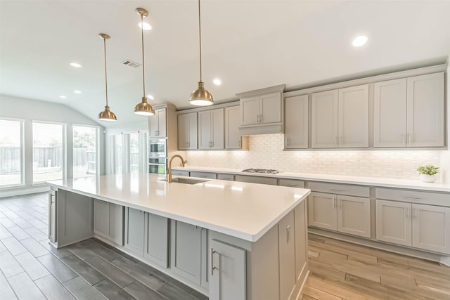 20519 Grazing Foal Ln, Tomball, TX 77377 - kitchen featuring gray cabinetry, decorative backsplash, light wood-style floors, light countertops, and a kitchen island with sink
