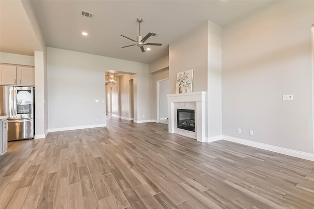 20519 Grazing Foal Ln, Tomball, TX 77377 - unfurnished living room with a ceiling fan, light wood-style flooring, a chandelier, a glass covered fireplace, and recessed lighting