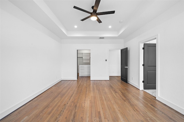 1011 E 28th St, Houston, TX 77009 - unfurnished bedroom with a raised ceiling, wood finished floors, a walk in closet, recessed lighting, and a ceiling fan