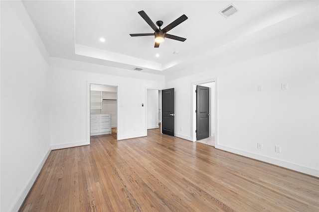 1011 E 28th St, Houston, TX 77009 - unfurnished bedroom with a raised ceiling, light wood-type flooring, a walk in closet, recessed lighting, and ceiling fan