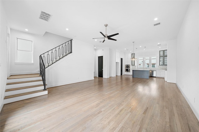 1011 E 28th St, Houston, TX 77009 - unfurnished living room featuring a ceiling fan, stairs, light wood finished floors, recessed lighting, and a chandelier