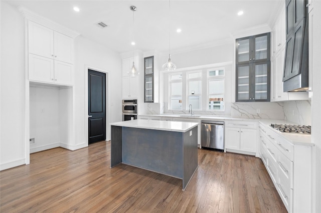 1011 E 28th St, Houston, TX 77009 - kitchen featuring appliances with stainless steel finishes, wood finished floors, glass insert cabinets, backsplash, and recessed lighting