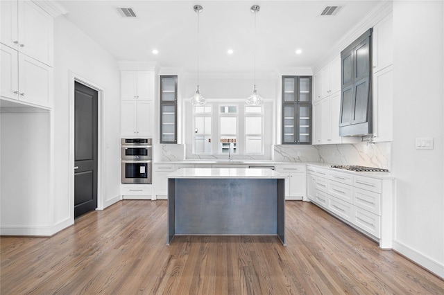 1011 E 28th St, Houston, TX 77009 - kitchen with double oven, gas cooktop, tasteful backsplash, glass insert cabinets, and wood finished floors