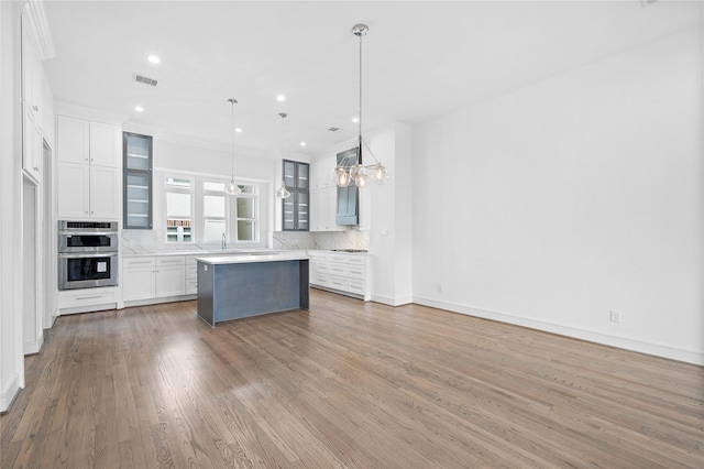 1011 E 28th St, Houston, TX 77009 - kitchen featuring double oven, light countertops, backsplash, a center island, and white cabinets