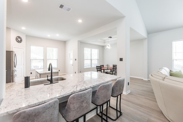 1563 Rd 66114, Dayton, TX 77535 - kitchen featuring freestanding refrigerator, a breakfast bar area, light stone countertops, a peninsula, and light wood-style floors