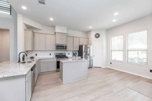 1563 Rd 66114, Dayton, TX 77535 - kitchen with stainless steel appliances, gray cabinets, backsplash, a kitchen island, and light wood-type flooring