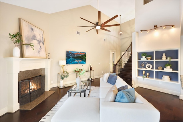5523 Harvest Oak Landing Dr, Spring, TX 77386 - living area featuring a warm lit fireplace, ceiling fan, wood finished floors, stairway, and high vaulted ceiling