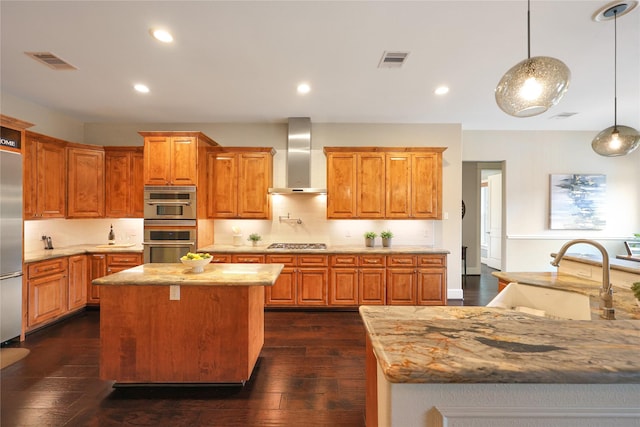 5523 Harvest Oak Landing Dr, Spring, TX 77386 - kitchen featuring wall chimney range hood, a kitchen island, appliances with stainless steel finishes, dark wood-style flooring, and light stone countertops