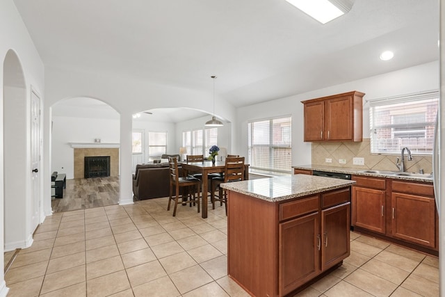 20930 Morgan Knoll Ln, Katy, TX 77449 - kitchen with light tile patterned flooring, decorative backsplash, a kitchen island, light stone countertops, and a fireplace