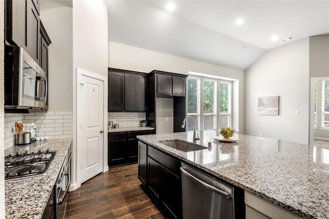 16711 Ramsay Cascades Dr, Humble, TX 77346 - kitchen featuring stainless steel appliances, lofted ceiling, light stone countertops, decorative backsplash, and dark wood-style floors