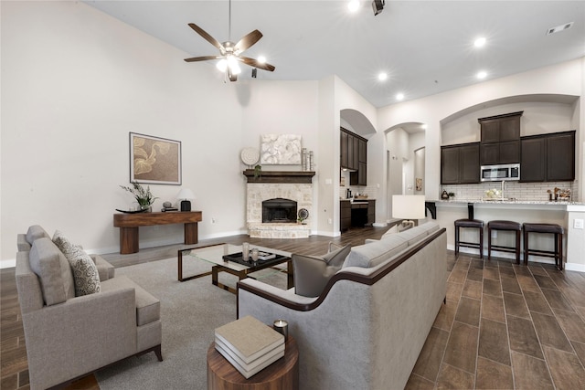 16711 Ramsay Cascades Dr, Humble, TX 77346 - living room featuring ceiling fan, recessed lighting, dark wood-style floors, arched walkways, and a stone fireplace