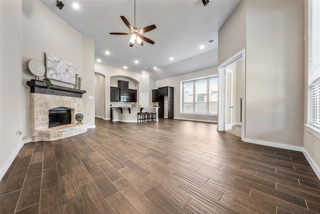 16711 Ramsay Cascades Dr, Humble, TX 77346 - living room with ceiling fan, dark wood-style floors, a stone fireplace, lofted ceiling, and arched walkways