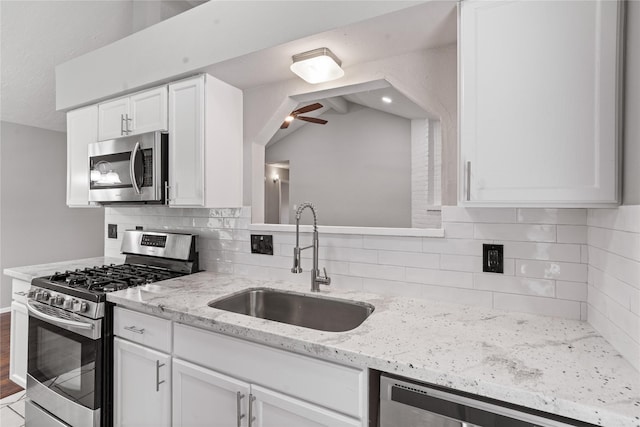 2031 Oakwell Ln, Katy, TX 77449 - kitchen featuring appliances with stainless steel finishes, ceiling fan, white cabinets, tasteful backsplash, and light stone countertops