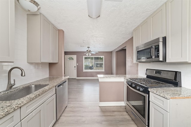 9333 Fairland Dr, Houston, TX 77051 - kitchen with stainless steel appliances, a textured ceiling, light wood finished floors, ceiling fan, and decorative backsplash