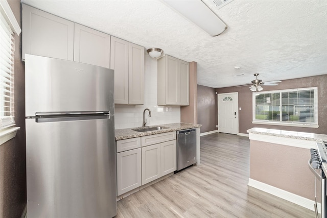 9333 Fairland Dr, Houston, TX 77051 - kitchen featuring appliances with stainless steel finishes, ceiling fan, light wood-style flooring, tasteful backsplash, and light stone counters