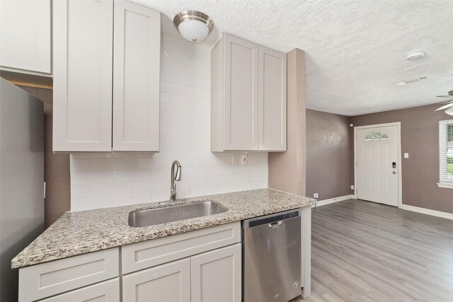 9333 Fairland Dr, Houston, TX 77051 - kitchen featuring appliances with stainless steel finishes, backsplash, light wood-type flooring, light stone counters, and a textured ceiling
