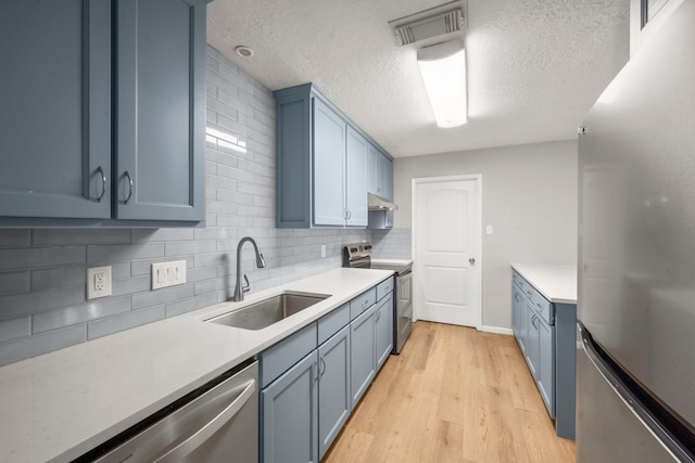 14902 Forest Lodge Dr, Houston, TX 77070 - kitchen featuring stainless steel appliances, blue cabinetry, light countertops, tasteful backsplash, and a textured ceiling