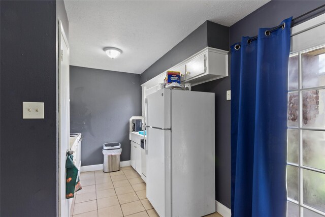 3412 Lantern Ln, Baytown, TX 77521 - kitchen with freestanding refrigerator, light tile patterned flooring, a textured ceiling, and white cabinets