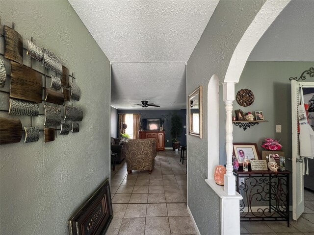 3412 Lantern Ln, Baytown, TX 77521 - hallway featuring arched walkways, a textured ceiling, a textured wall, and tile patterned floors