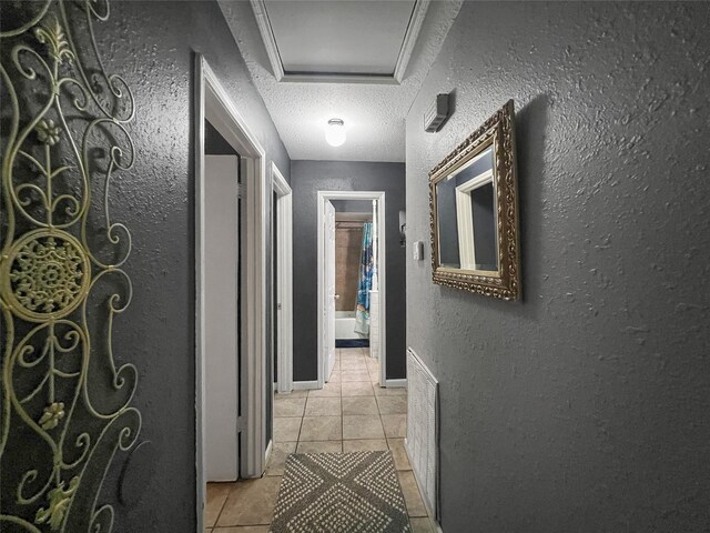 3412 Lantern Ln, Baytown, TX 77521 - corridor with light tile patterned floors, a textured wall, a textured ceiling, and attic access