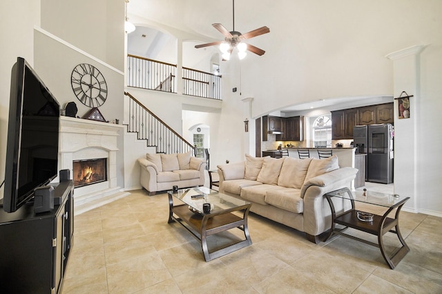 20692 Oakhurst Meadows Dr, Porter, TX 77365 - living area featuring a ceiling fan, a towering ceiling, a high end fireplace, arched walkways, and light tile patterned floors