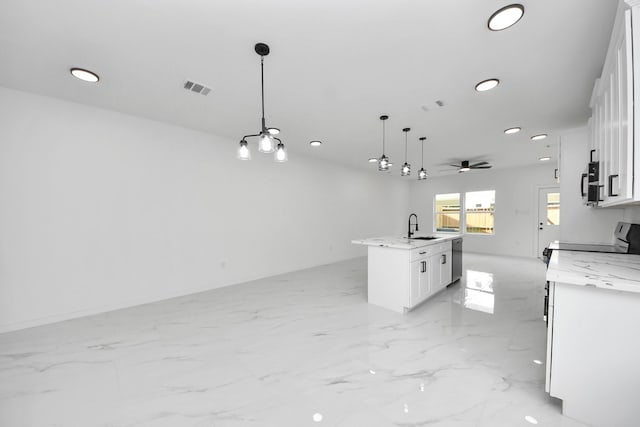 8023 Brandon St, Houston, TX 77051 - kitchen featuring recessed lighting, light marble finish floors, a kitchen island with sink, white cabinetry, and pendant lighting