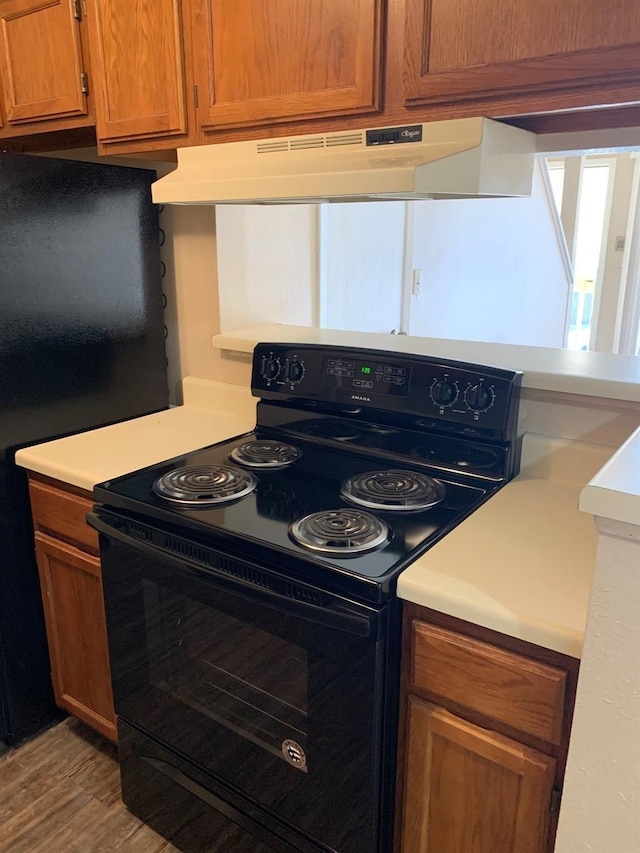 2501 Gulf Fwy Unit 246D, Dickinson, TX 77539 - kitchen featuring black range with electric stovetop, under cabinet range hood, light countertops, light wood finished floors, and brown cabinets
