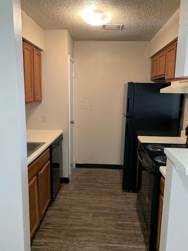 2501 Gulf Fwy Unit 246D, Dickinson, TX 77539 - kitchen featuring black appliances, under cabinet range hood, dark wood-style floors, light countertops, and a textured ceiling