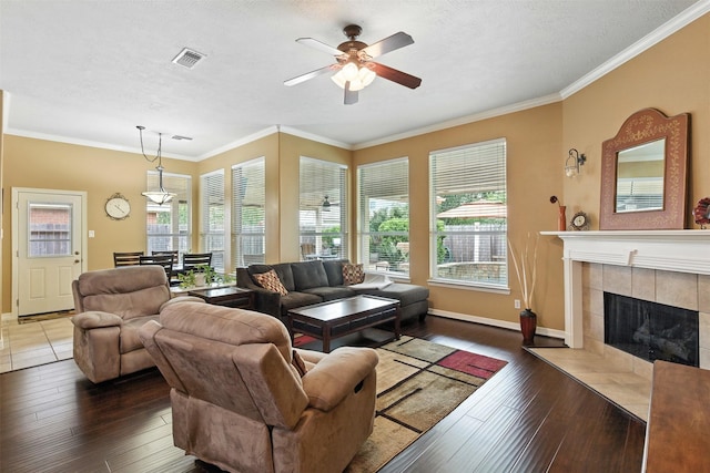 11506 Amber Canyon Dr, Houston, TX 77095 - living area with a ceiling fan, a tiled fireplace, hardwood / wood-style floors, crown molding, and a textured ceiling
