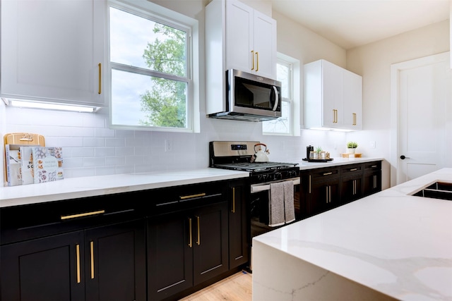 1306 Evelyn St, Houston, TX 77009 - kitchen with appliances with stainless steel finishes, white cabinets, backsplash, and dark cabinetry