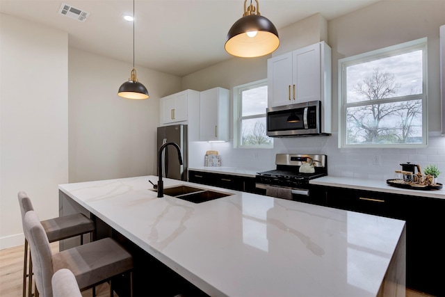 1306 Evelyn St, Houston, TX 77009 - kitchen with appliances with stainless steel finishes, tasteful backsplash, a kitchen island with sink, and light stone countertops