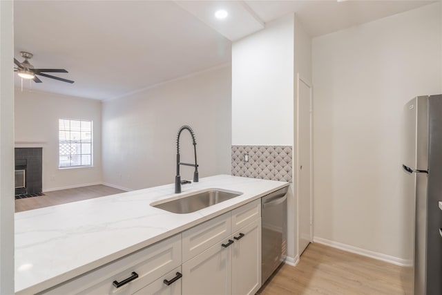 9850 Pagewood Ln Unit 909, Houston, TX 77042 - kitchen with stainless steel appliances, light stone counters, light wood-style floors, white cabinetry, and ceiling fan
