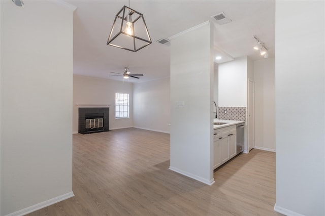 9850 Pagewood Ln Unit 909, Houston, TX 77042 - unfurnished living room with light wood-type flooring, a ceiling fan, a fireplace, and crown molding