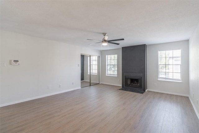 9850 Pagewood Ln Unit 909, Houston, TX 77042 - unfurnished living room featuring light wood-style flooring, healthy amount of natural light, a ceiling fan, and a large fireplace