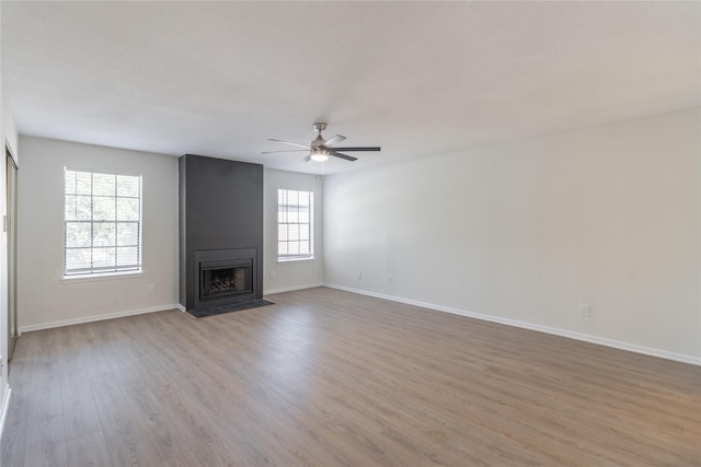 9850 Pagewood Ln Unit 909, Houston, TX 77042 - unfurnished living room featuring light wood-style floors, a ceiling fan, and a large fireplace