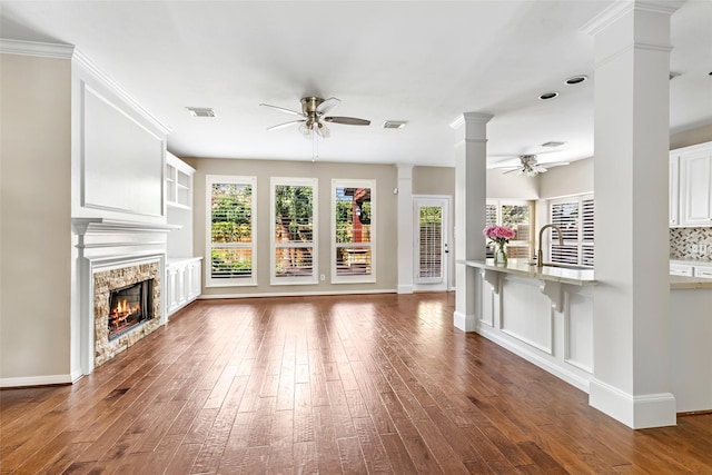 7127 Vermejo Park Ln, Humble, TX 77346 - unfurnished living room with ceiling fan, wood-type flooring, a stone fireplace, and ornate columns