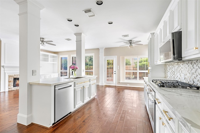 7127 Vermejo Park Ln, Humble, TX 77346 - kitchen with stainless steel appliances, ceiling fan, ornate columns, dark wood-style flooring, and recessed lighting