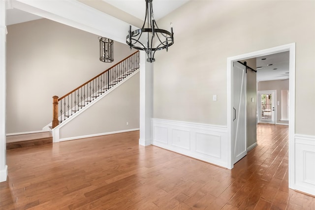 7127 Vermejo Park Ln, Humble, TX 77346 - unfurnished dining area with a chandelier, a barn door, wood finished floors, and stairway