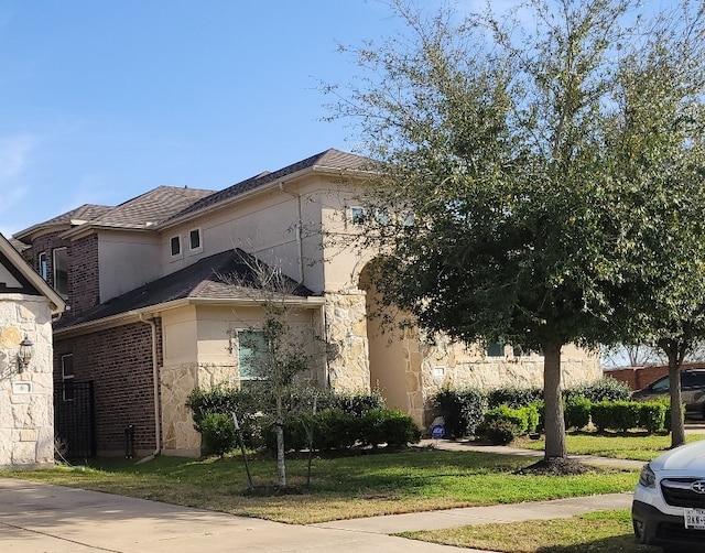 2 Chalice Trl, Sugar Land, TX 77498 - view of front facade with stucco siding, stone siding, a front lawn, and brick siding